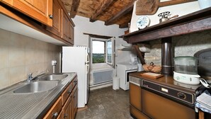 A kitchen with wooden cabinets, a built-in oven, and a window with a view. - Holiday Home 'La Maison Bayle' with Mountain View, Private Garden & Wi-Fi (Mauvezin)
