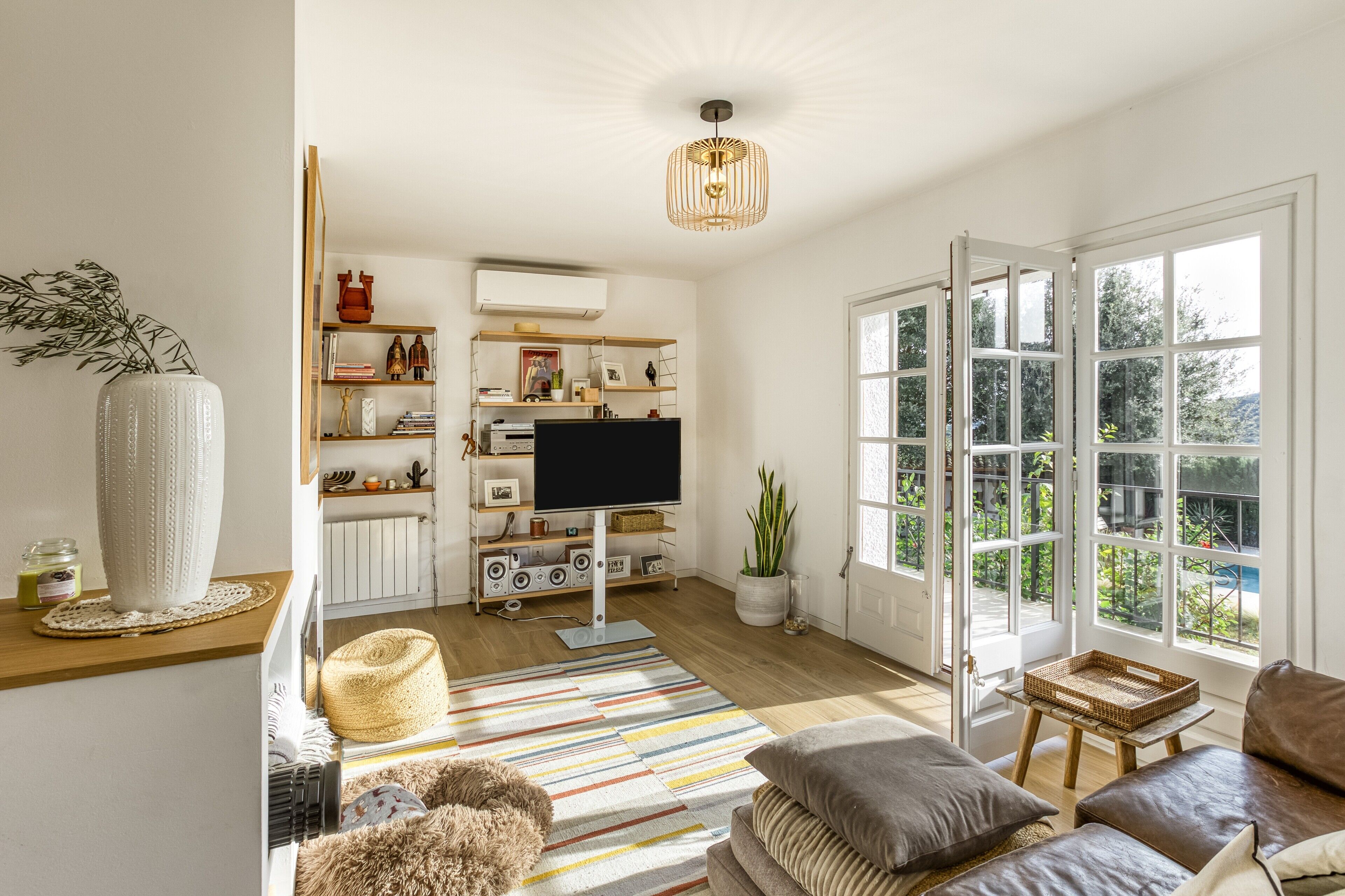 A living room with a TV, sofa, and large windows.