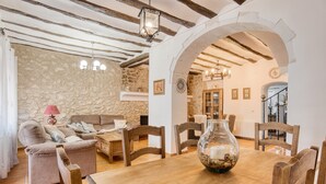 A rustic interior with stone walls, wooden furniture, and a dining table with a vase centerpiece. - Country House 'Casa Amparo' with Mountain View, Private Pool and Wi-Fi (Alcoleja)
