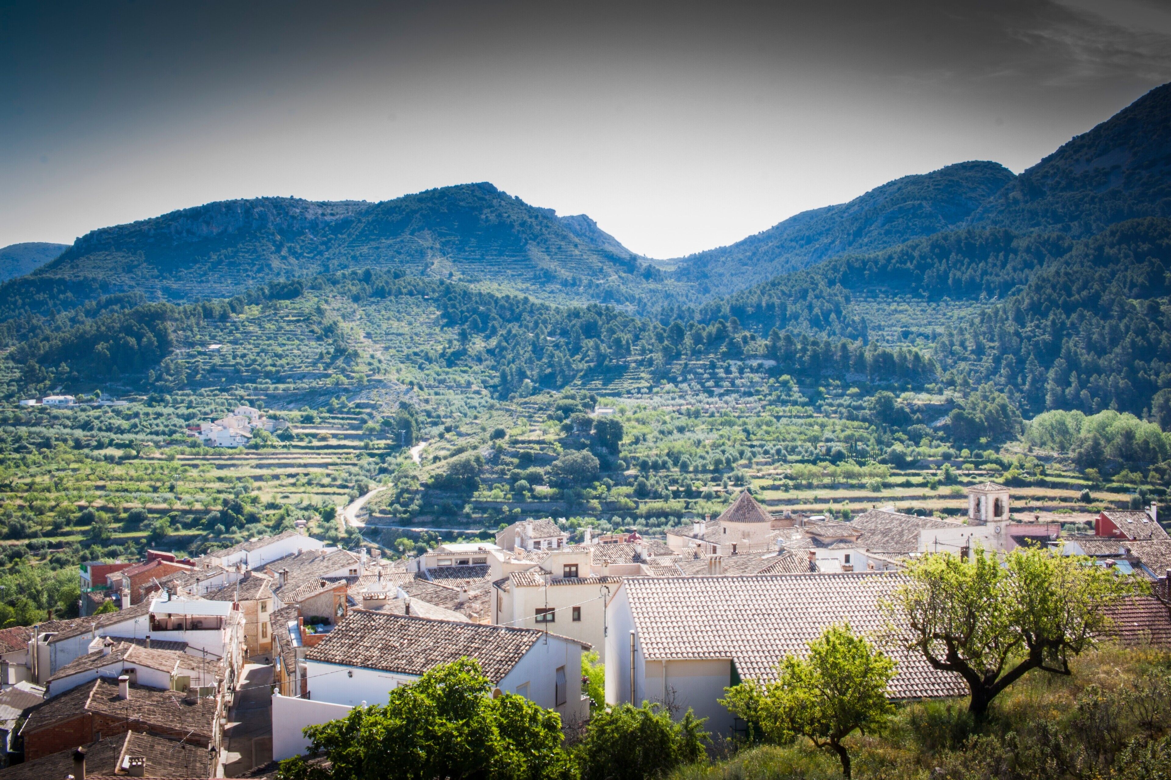 Paesaggio montuoso con campi a terrazza e un piccolo villaggio con edifici tradizionali.