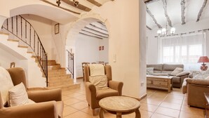 A spacious living area with a staircase, a sofa set, and a dining table. - Country House 'Casa Amparo' with Mountain View, Private Pool and Wi-Fi (Alcoleja)