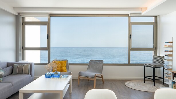 Una sala de estar moderna con un ventanal grande, un sofá, una mesa y una silla.