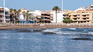 Un hotel costero con varios pisos, balcones y vista al mar.