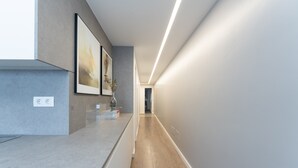 Un pasillo moderno con mostrador de cocina, obras de arte enmarcadas y un jarrón.
