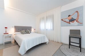 Une chambre à coucher moderne avec un lit, des tables de chevet, une chaise et un tableau au mur.