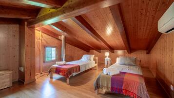 Un dormitorio abuhardinado con paneles de madera, dos camas, una ventana y una mesita.