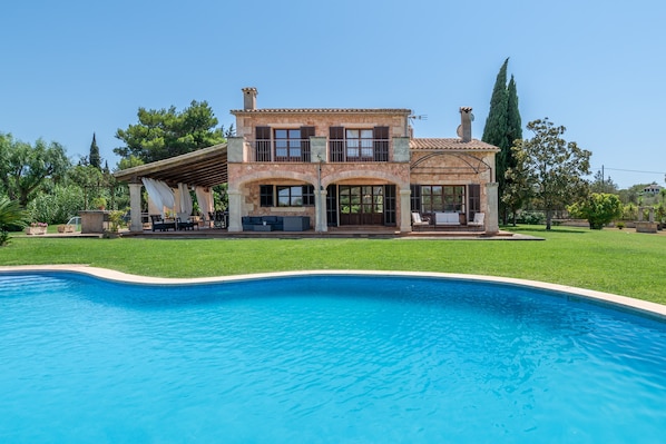 A two-story house with a swimming pool in front.