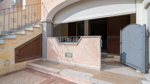 Ein Gebäudeeingang mit einer Treppe, einem Metallgitter und einer Holztür.