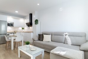 Una sala de estar moderna con un sofá, una mesa de centro de vidrio y un comedor con sillas y una mesa.