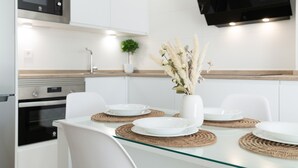A modern kitchen with white cabinetry, a microwave, an oven, and a flat-screen TV mounted above the counter. - Apartment 'Calderon' with Air Conditioning (Barbate)