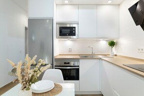 Una cocina moderna con armarios blancos, electrodomésticos de acero inoxidable y encimera de madera.