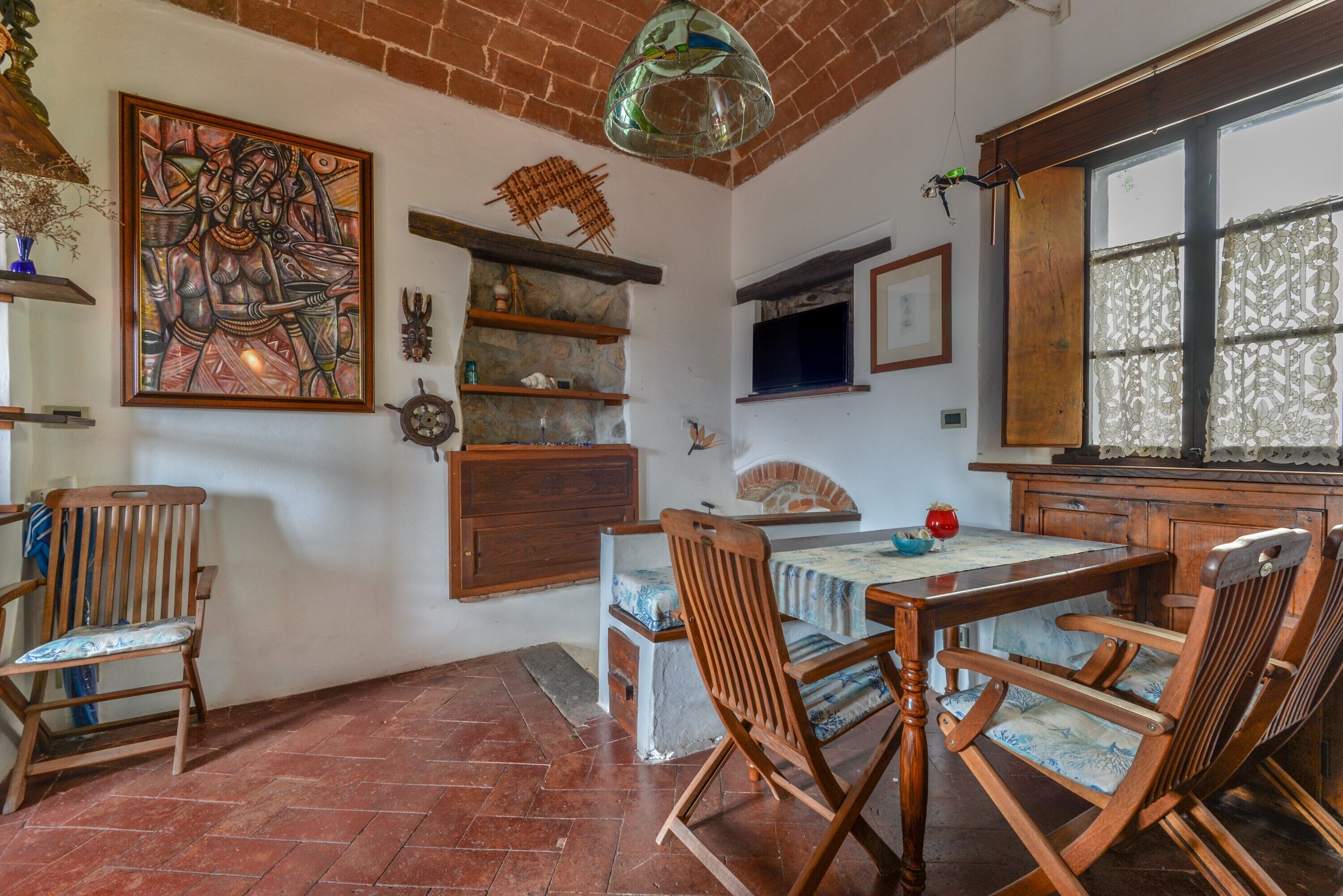 Un comedor con techo de ladrillo, mobiliario de madera y un cuadro grande en la pared.