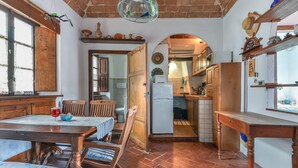 Una cocina rústica con muebles de madera, un comedor con mesa y sillas, y vistas al comedor contiguo.