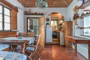 Une cuisine rustique avec des meubles en bois, un coin repas avec une table et des chaises, et une vue sur la salle à manger adjacente.