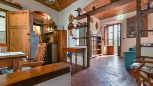 Un interior rústico con muebles de madera, suelo de ladrillo y vistas a través de una puerta abierta.