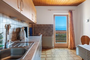 Une cuisine équipée d’un évier, d’une cuisinière et de placards, d’un radiateur, et offrant une vue par une fenêtre.