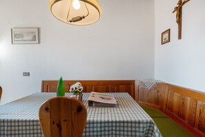 Un coin repas avec une nappe à carreaux, des chaises en bois, une bouteille verte et une tête de lit en bois.