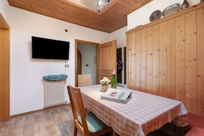 Un comedor con una mesa, sillas, un radiador, un televisor y paneles de madera.