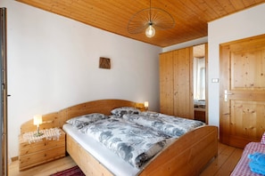 Un dormitorio con cama de madera, lámparas de noche, techo de madera y un armario de madera.