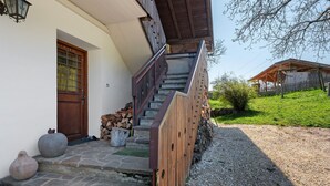 Un escalier en bois menant à une porte dotée d’une fenêtre, un mur en pierre et une clôture en bois.