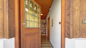 A wooden door with a glass panel, a hallway with a tiled floor, and a staircase leading to another room. - Apartment 'Theresa' with Mountain View, Shared Garden and Wi-Fi (Appiano)