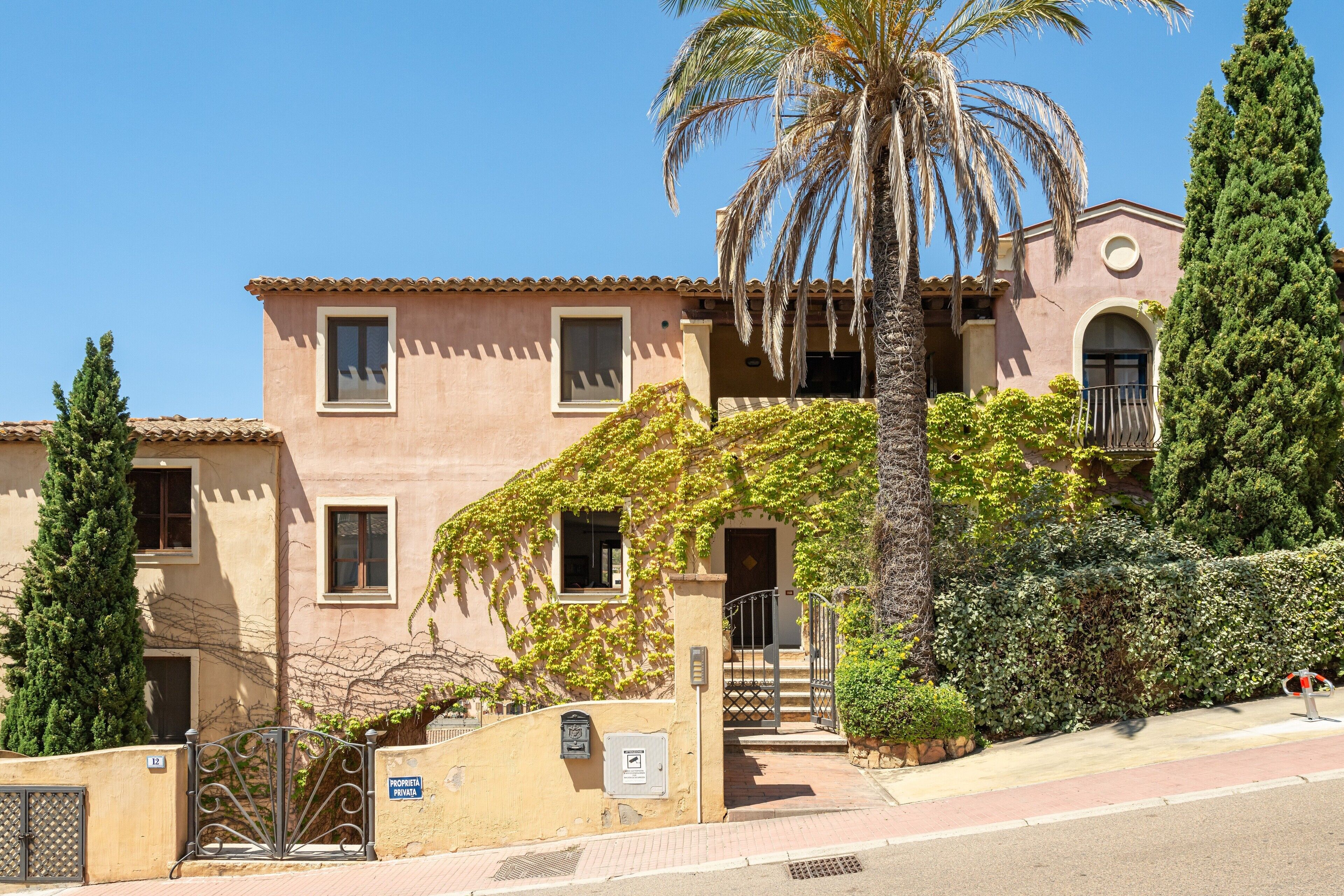A two-story building with a tiled roof, a balcony, and a gate.