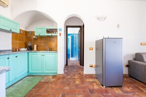 Une cuisine avec des armoires de couleur turquoise, un réfrigérateur en acier inoxydable et un sol carrelé.