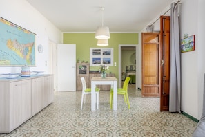 A dining area with a table and chairs, a map on the wall, and a kitchen in the background.