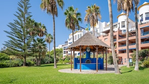 Ein Kiosk mit blauer und weißer Struktur, umgeben von Palmen und einem gepflegten Rasen.