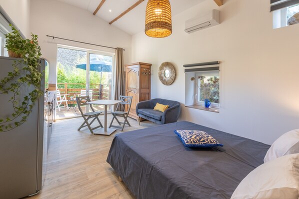 A bedroom with a bed, a sofa, a dining table, and a window.