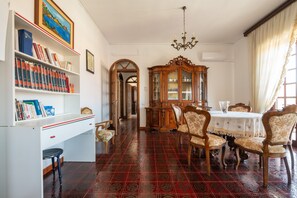 Um quarto com uma estante, uma mesa de jantar com cadeiras, um candelabro e um armário de madeira.