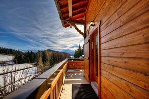 Une cabane en bois dotée d’un balcon donnant sur un paysage enneigé et des montagnes.