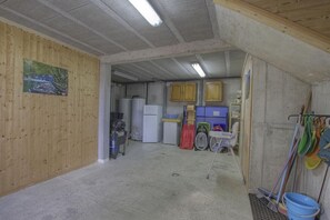Une pièce avec un mur en bois, un tableau, un réfrigérateur, une machine à laver, un évier et des ustensiles de nettoyage.