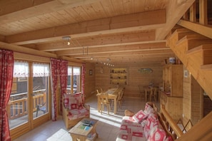 Ein Holzhütten-Innenraum mit Essbereich, Sofa und einer Treppe.