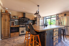 Une cuisine moderne dotée d’un îlot central, de tabourets de bar, d’une cuisinière, d’un four et d’un réfrigérateur.