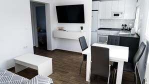 A modern kitchen with white cabinets, a built-in microwave, and a dining area with a white table and black chairs. - Apartment 'Apartamento Dialma' with Mountain Views, Wi-Fi, and Air Conditioning (Vejer de la Frontera)