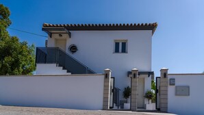 A two-story building with a white exterior, a tiled roof, a black staircase, and a gated entrance. - Apartment 'Apartamento Dialma' with Mountain Views, Wi-Fi, and Air Conditioning (Vejer de la Frontera)