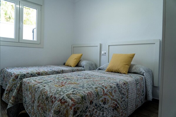 Una habitación con dos camas, cada una con ropa de cama estampada y una almohada amarilla.