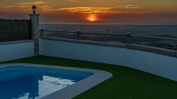 Piscina en la azotea con vistas a aerogeneradores y al atardecer.