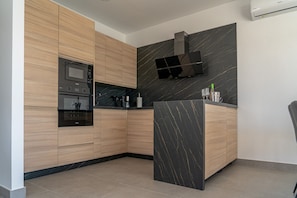 A modern kitchen with built-in appliances, a marble backsplash, and a black range hood.