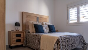 Une chambre à coucher avec un lit, des tables de chevet, une lampe et une fenêtre.
