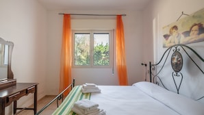 Une chambre à coucher avec un lit, un bureau, une fenêtre avec des rideaux et un tableau au mur.