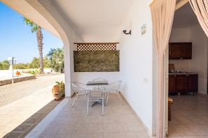 Un patio con tavolo e sedie, vista sulla strada e angolo cottura.