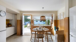 Una cucina moderna con zona pranzo, arredi in legno e vista attraverso una porta aperta.