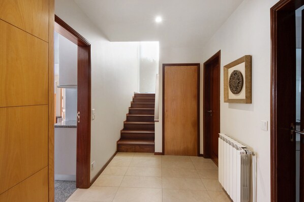A hallway with a wooden door, a staircase, and a radiator.