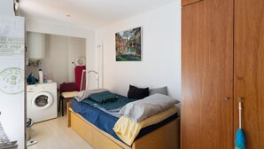 Un dormitorio con cama, lavadora, radiador y un cuadro en la pared.