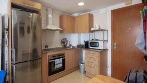 Una cocina moderna con electrodomésticos de acero inoxidable, armarios de madera y salpicadero de azulejos.