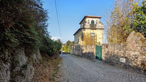 Une rue pavée menant à un bâtiment doté d’une porte verte et d’une tour.