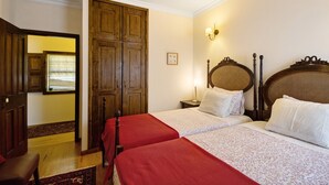 Une chambre d’hôtel avec deux lits, une armoire en bois et une table de chevet avec une lampe.