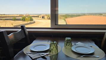 A table set for two with a view of a rural landscape through a window.